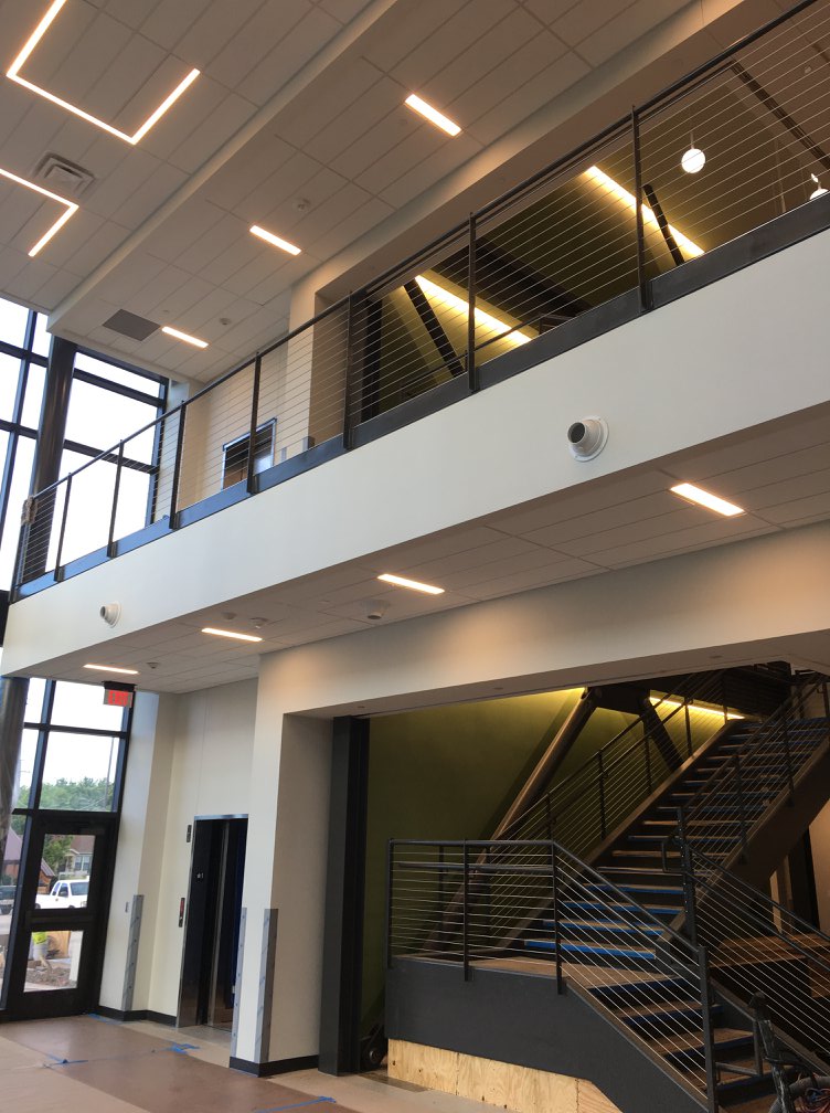 Completed commercial electrical installation by C&G Electric Inc — modern two-story North Texas building with linear LED lighting, mezzanine, and staircase, ready for occupancy
