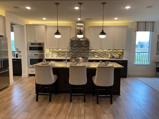 Residential kitchen lighting by C&G Electric Inc — pendant lights over island with recessed cans, white cabinetry, and mosaic tile backsplash in a North Texas home